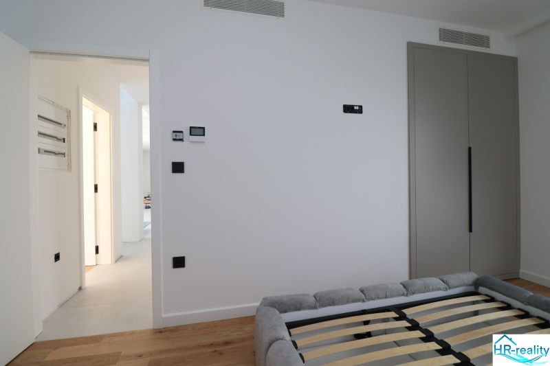 Schlafzimmer in der Villa mit Schrank, Bett und Boden in Holzoptik.