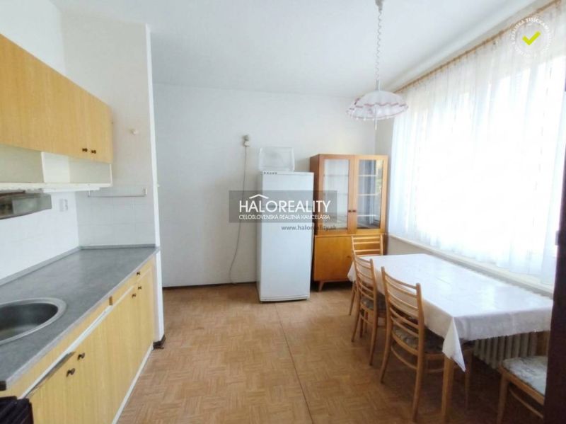 Küche in einer Einzimmerwohnung mit Esstisch und Boden in Holzoptik.