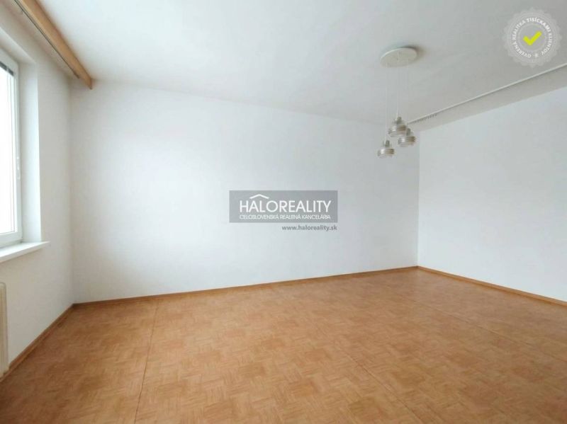Ein Zimmer in einer Einzimmerwohnung mit weißen Wänden und einem Boden in Holzoptik.