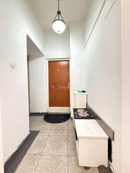 Ein Flur mit weißen Wänden und braunen Türen in einer Zweizimmerwohnung.