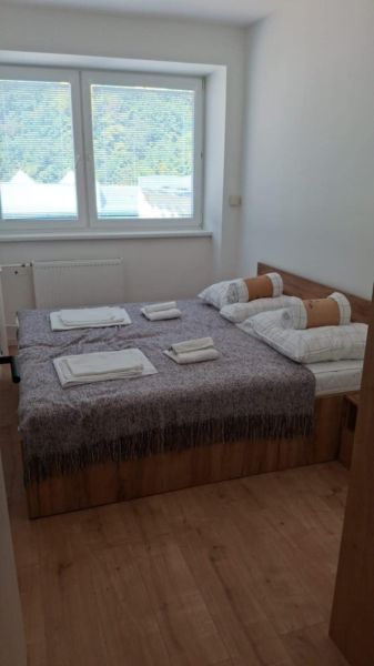 Schlafzimmer mit Bett und Fenster, Boden mit Holzdekor in einer 2-Zimmer-Wohnung.