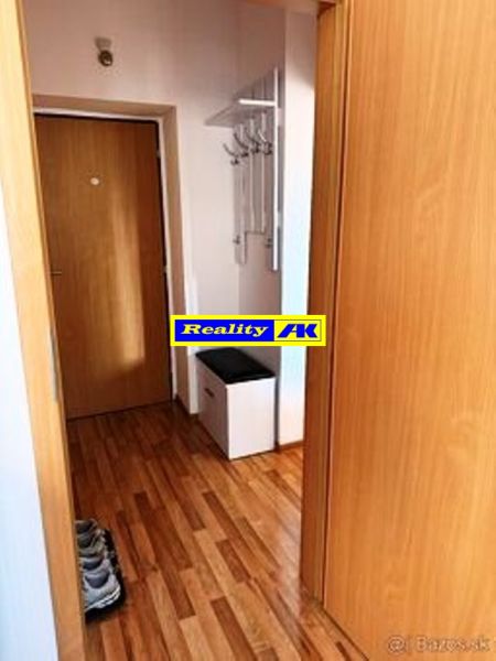 Der Flur in einer Einzimmerwohnung mit einem Boden in Holzdekor und einem Kleiderhaken.