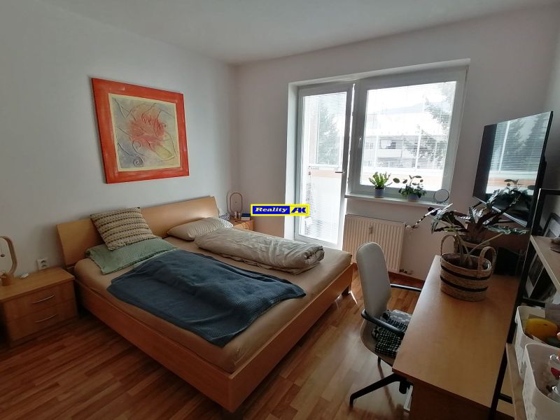 Helle 1-Zimmer-Wohnung mit Holzboden, Bett und Tisch.