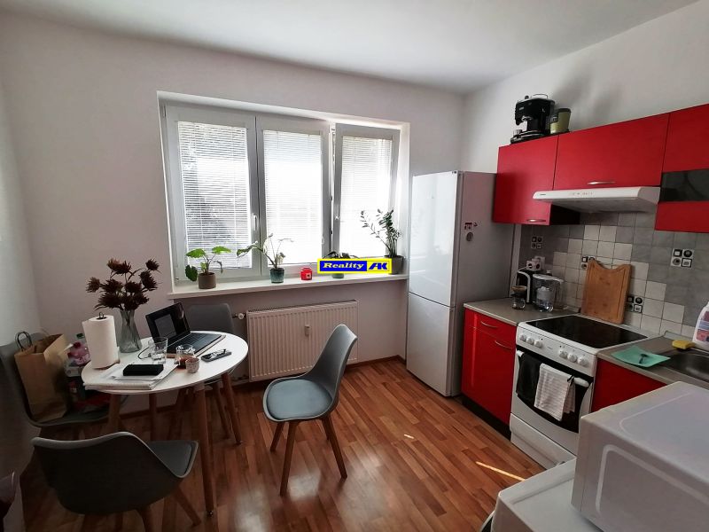 Küche in einer Einzimmerwohnung mit Holzboden und roter Küchenzeile.
