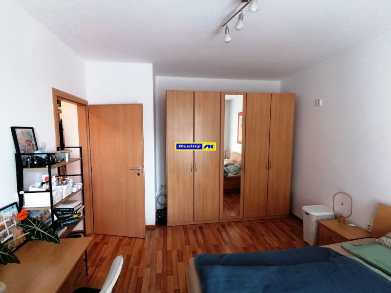 Schlafzimmer in einer Einzimmerwohnung mit Holzboden, Kleiderschrank und Schreibtisch.