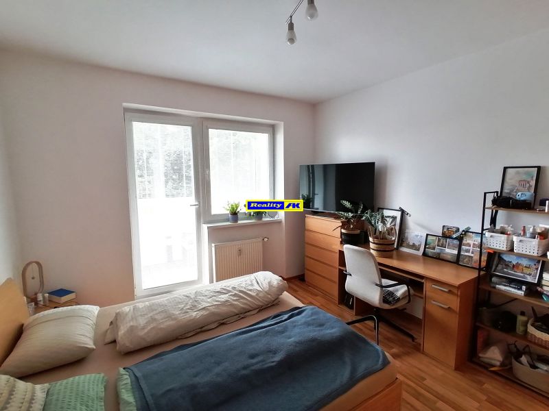 Schlafbereich in einer Einzimmerwohnung mit Holzboden und Schreibtisch.
