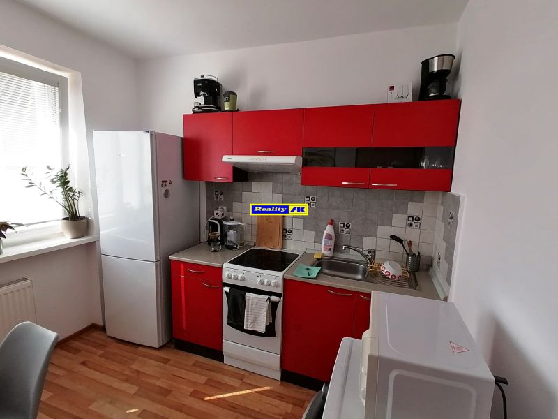 Küche mit roten Schränken und Holzdekorboden in einer Einzimmerwohnung.