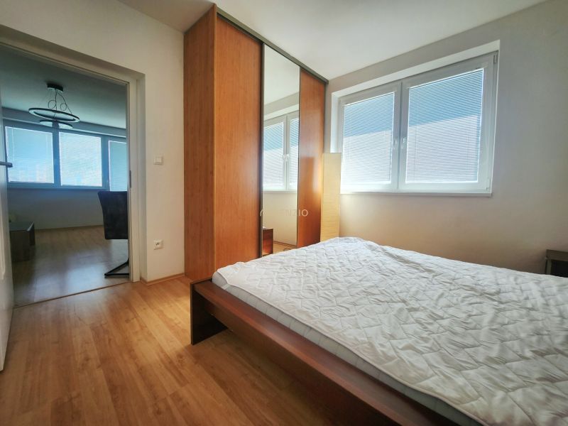 Schlafzimmer mit großem Schrank und Bett, Boden mit Holzdekor in einer 3-Zimmer-Wohnung.
