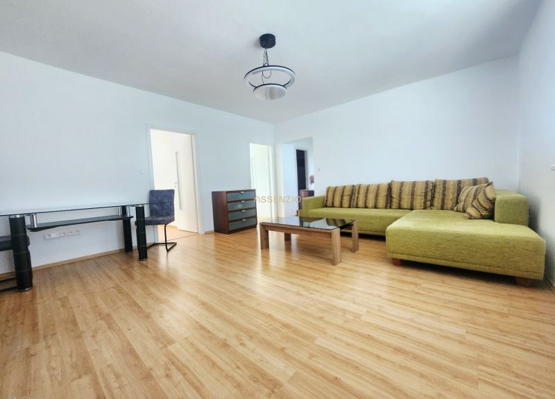 Wohnzimmer mit Sofa, Tisch und Boden in Holzoptik in einer 3-Zimmer-Wohnung.