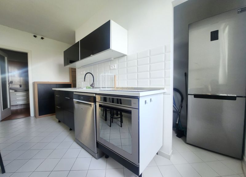 Küche mit weißen Fliesen, Spülmaschine aus Edelstahl und Kühlschrank in einer 3-Zimmer-Wohnung.