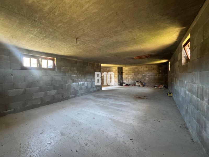 Innenraum einer im Bau befindlichen Hütte mit Betonwänden und -boden.
