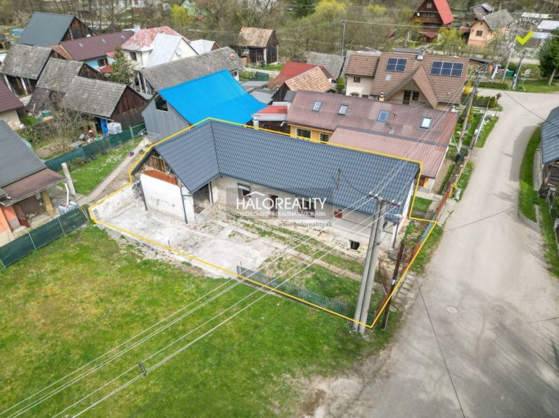 Ein Einfamilienhaus in Stupno mit einem niedrigen blauen Dachprofil, umgeben von benachbarten Gebäuden.