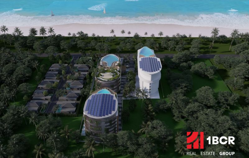 Wohnungsbau am Strand in Phuket mit modernen Gebäuden und Pools, umgeben von Palmen.
