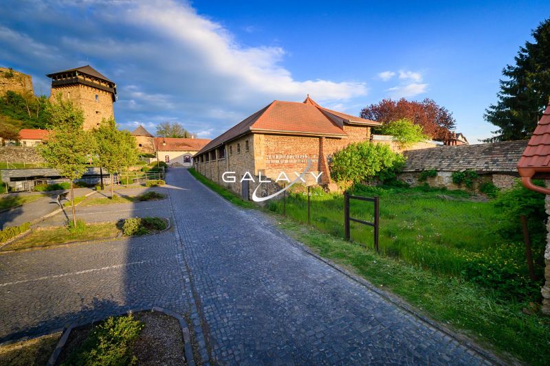Ein gepflasterter Gehweg entlang eines historischen Gebäudes auf einem Gewerbegrundstück in Fiľakovo.