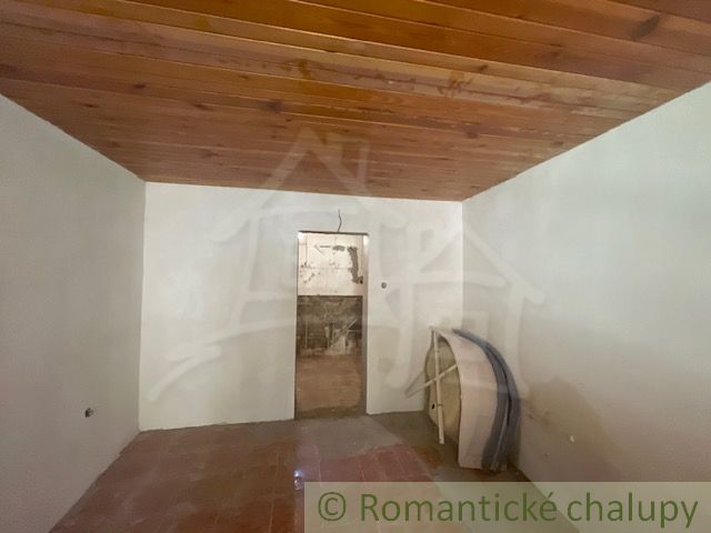 Ein Zimmer in einem Einfamilienhaus mit einem Keramikboden und einer Holzdecke.