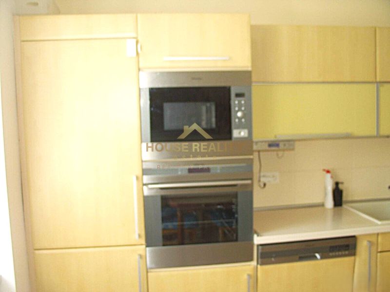 Küche in einer 2-Zimmer-Wohnung mit eingebauten Geräten und hellen Möbeln.