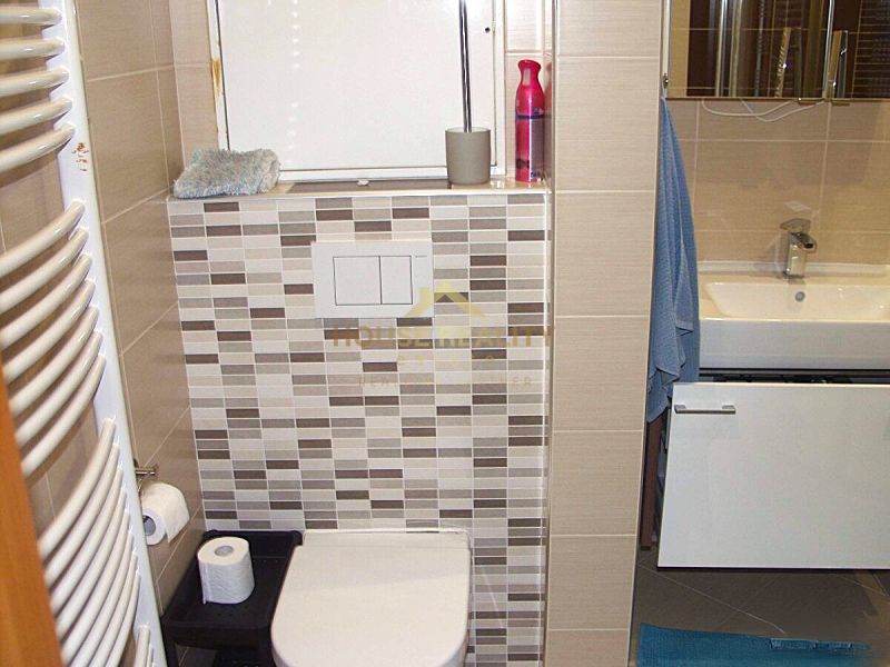 Badezimmer in einer 2-Zimmer-Wohnung mit Badewanne, Waschbecken und Fliesen in neutralen Farbtönen.
