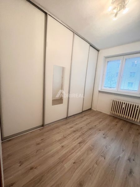Ein Zimmer in einer 3-Zimmer-Wohnung mit einem weißen Schrank und einem Boden in Holzoptik.