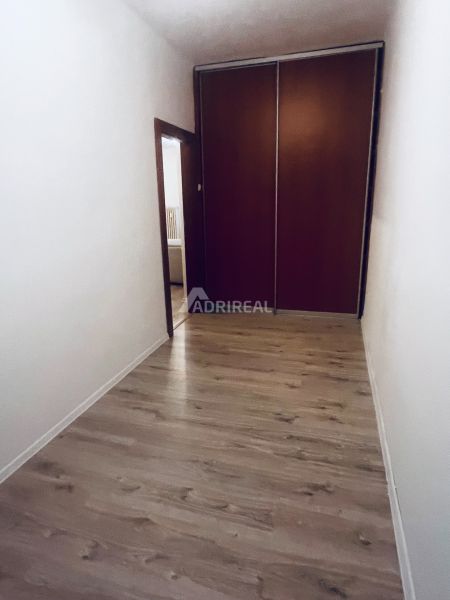 Flur mit Einbauschrank und Boden mit Holzdekor in einer 3-Zimmer-Wohnung.