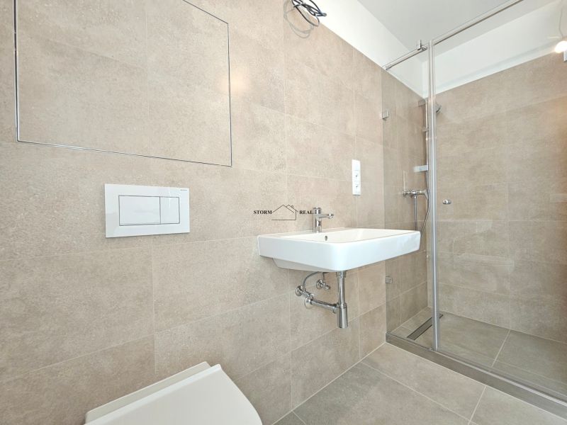 Badezimmer in einer Einzimmerwohnung mit Toilette, Duschkabine und Waschbecken im minimalistischen Stil.