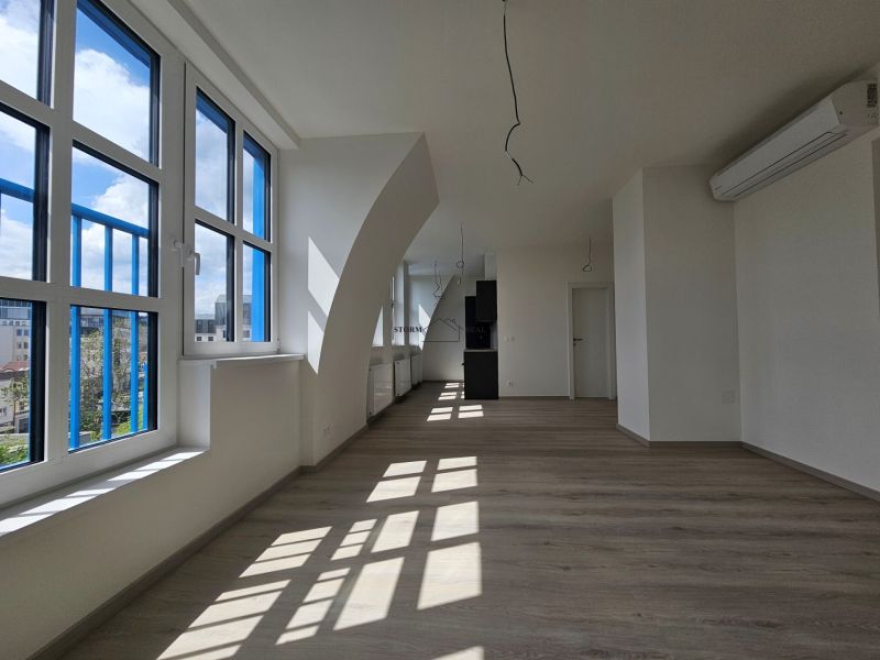 Ein geräumiges Zimmer mit großen Fenstern, Holzboden-Dekor in einer Einzimmerwohnung.