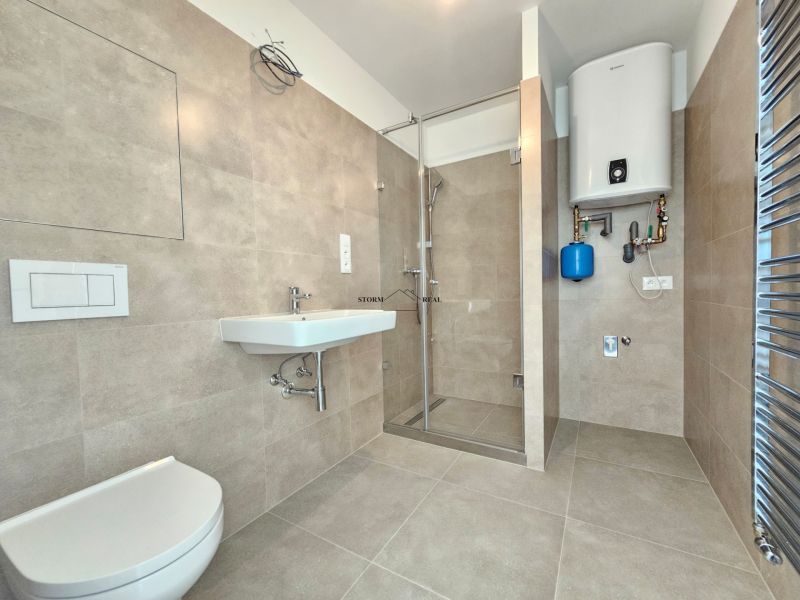 Badezimmer in einer Einzimmerwohnung mit Duschkabine und Gasboiler.