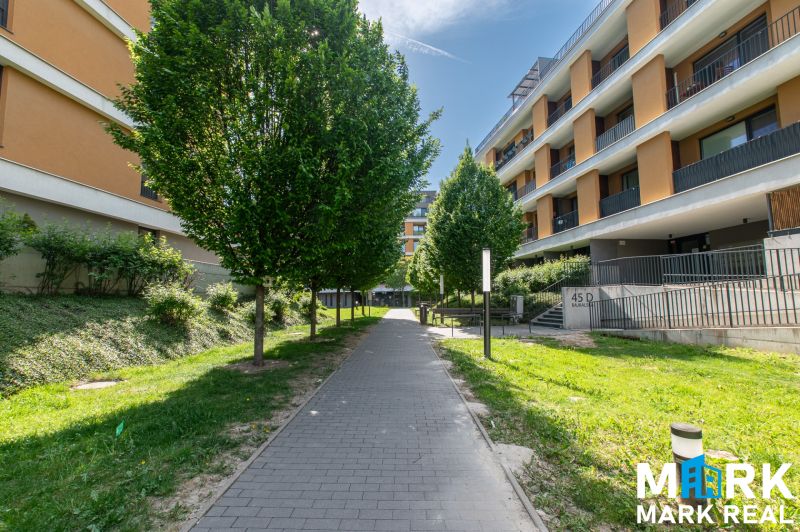 Bajkalská Straße in Bratislava mit Wohnhäusern und Bäumen entlang des Gehwegs.