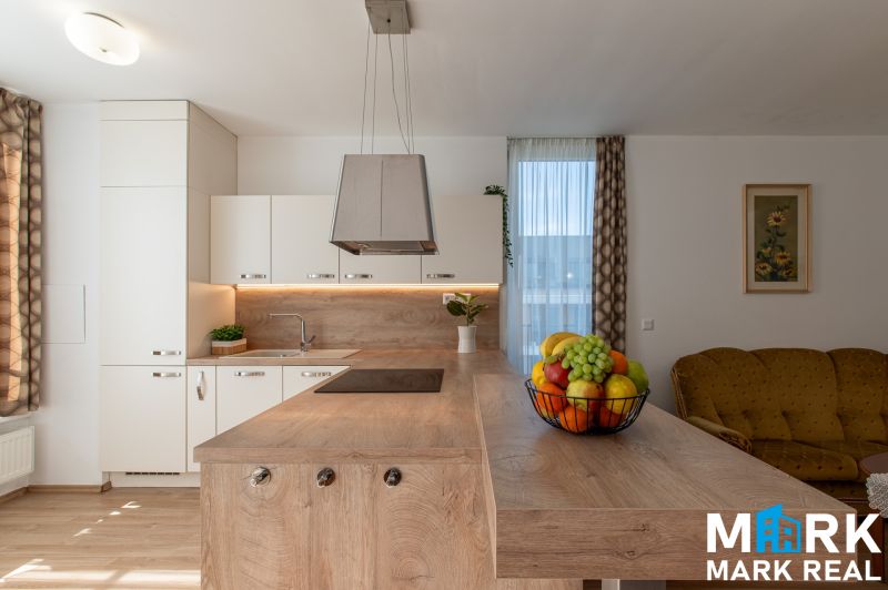 Küche mit Insel und Obst in einer 2-Zimmer-Wohnung, Boden mit Holzdekor.