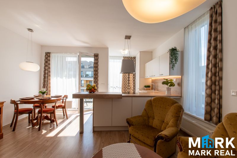 Wohnzimmer verbunden mit Küche, Esstisch, Boden mit Holzdekor, helle Vorhänge.