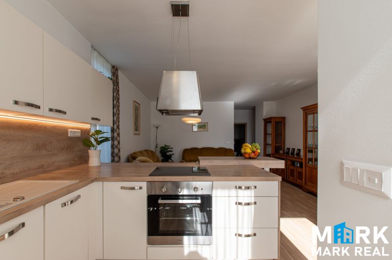 Küche in einer 2-Zimmer-Wohnung mit Holzboden und weißen Schränken.