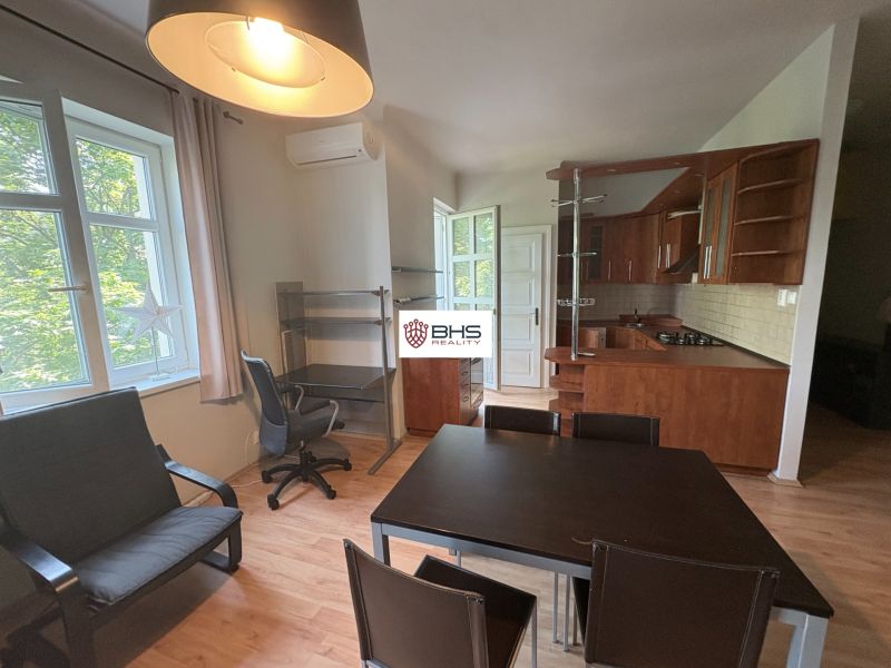 Wohnbereich mit Küche und Esstisch in einer 2-Zimmer-Wohnung, Boden mit Holzdekor.