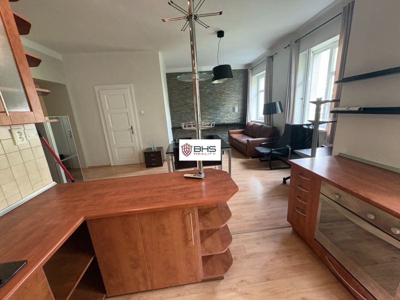 Wohnbereich in einer Zweizimmerwohnung mit Holzboden und Küchenzeile.