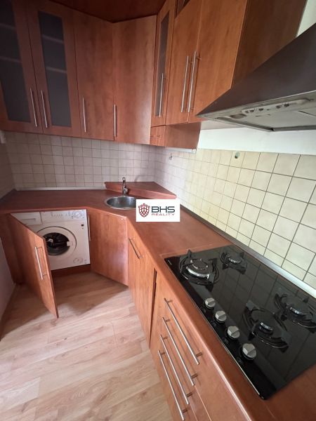 Küche in einer 2-Zimmer-Wohnung mit Holzboden und eingebauten Geräten.