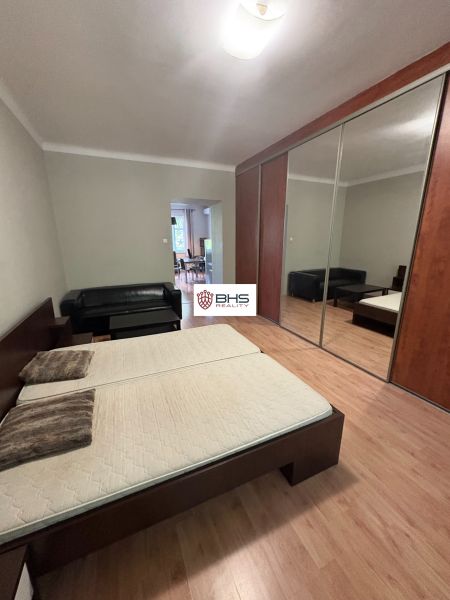 Schlafzimmer mit Doppelbett, Spiegelschrank und Holzboden in einer 2-Zimmer-Wohnung.