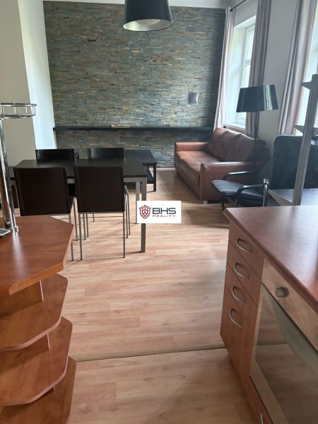 Innenraum einer 2-Zimmer-Wohnung mit Holzboden und einer Steinwand im Wohnzimmer.