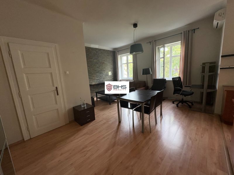 Innenraum einer 2-Zimmer-Wohnung mit Holzboden, Tisch und Stuhl.