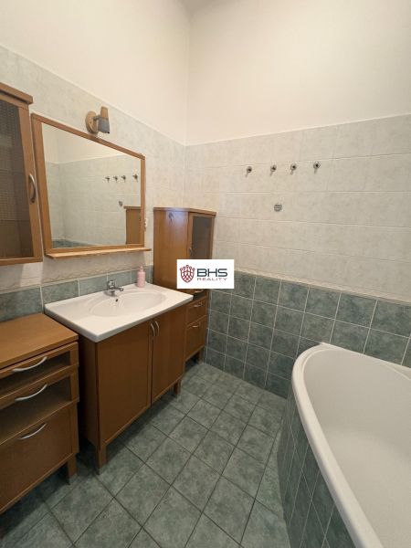 Badezimmer in einer 2-Zimmer-Wohnung mit Badewanne und Holzschrank.