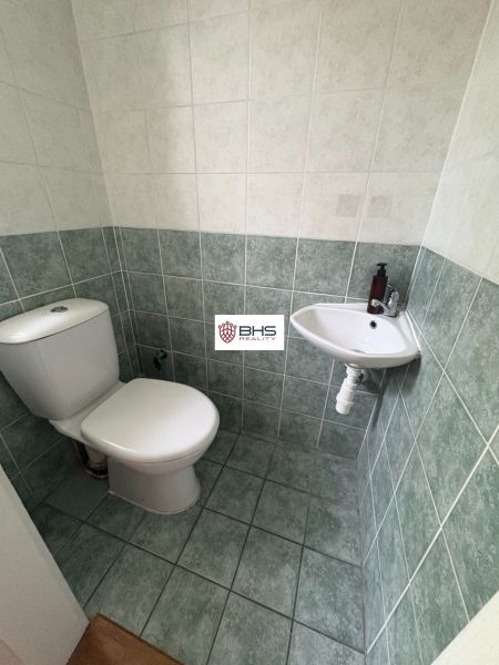 Toilette mit Fliesen und kleinem Waschbecken in einer Zweizimmerwohnung.