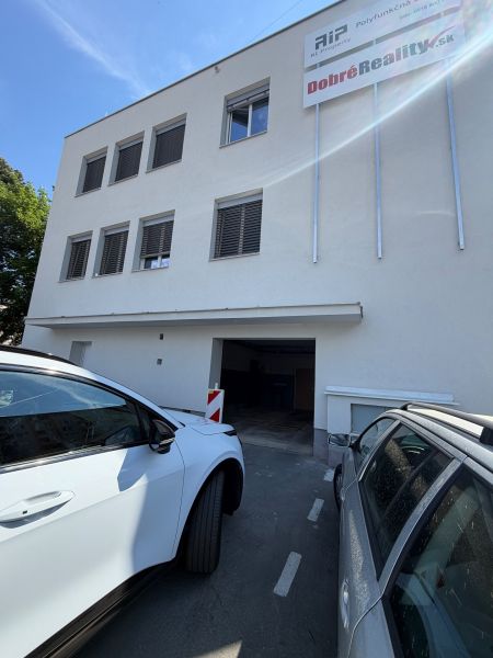Gebäude mit Garagen in der Langen Straße 3 in Prievidza, geparkte Autos vor dem Gebäude.