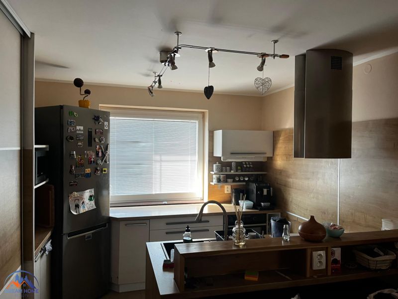 Küche in einem Einfamilienhaus mit einer Metall-Dunstabzugshaube, Boden mit Holzdekor.