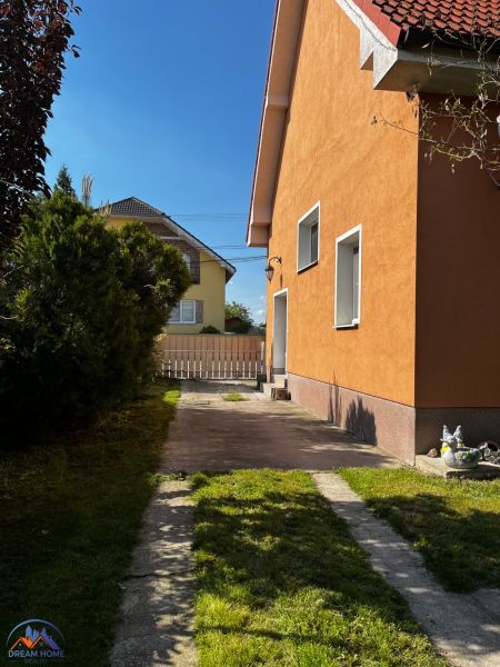 Ein Einfamilienhaus in Čalovec mit einer orangefarbenen Fassade, einem Rasen und einer befestigten Zufahrtsstraße.