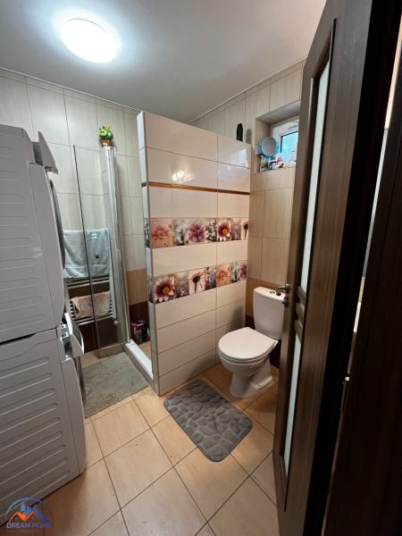Badezimmer in einem Einfamilienhaus mit Waschmaschine, Duschkabine und Toilette.