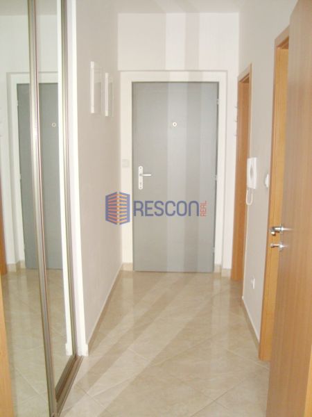 Eingangsbereich in einem Studio-Apartment mit Fliesenboden, Spiegelschrank und weißen Wänden.