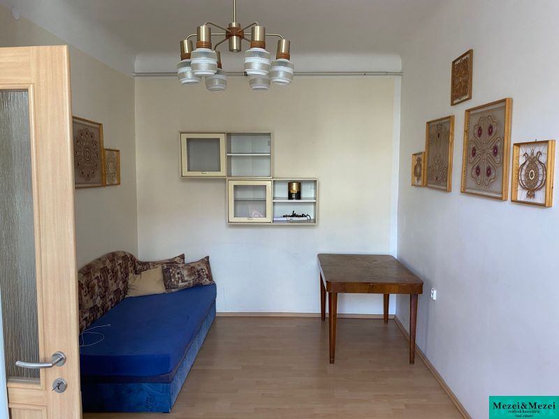 Ein Zimmer in einer 2-Zimmer-Wohnung mit einem blauen Sofa und einem Holztisch, Boden mit Holzdekor.