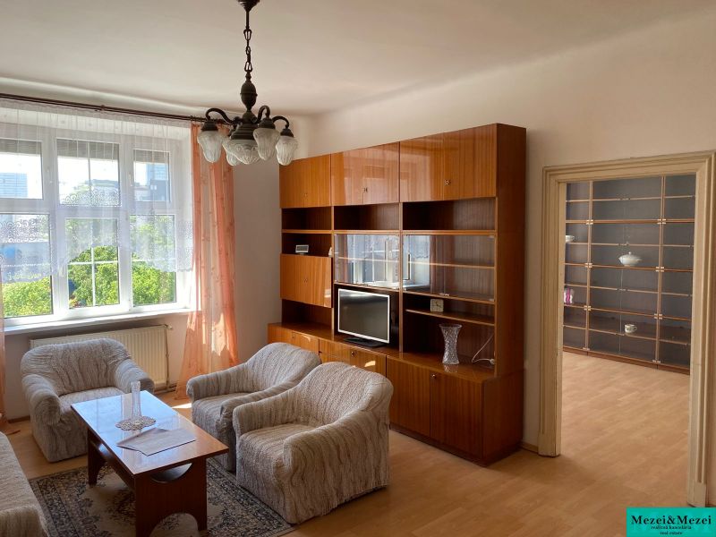 Wohnzimmer einer Zweizimmerwohnung mit Holzboden und bequemen Sitzgelegenheiten.