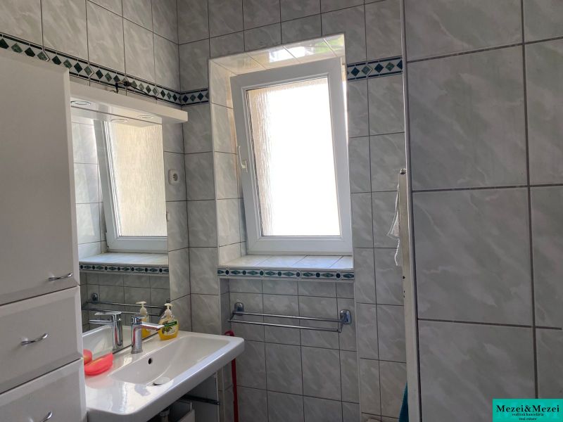 Badezimmer in einer 2-Zimmer-Wohnung mit Fliesen, Waschbecken und Fenster.