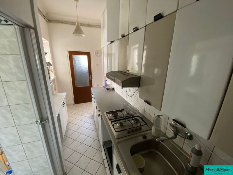 Küche in einer 2-Zimmer-Wohnung mit weißen Schränken und Fliesenboden.