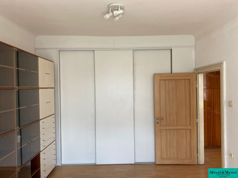 Innenraum einer 2-Zimmer-Wohnung mit einem weißen Schrank und einem Regalsystem, Boden mit Holzdekor.