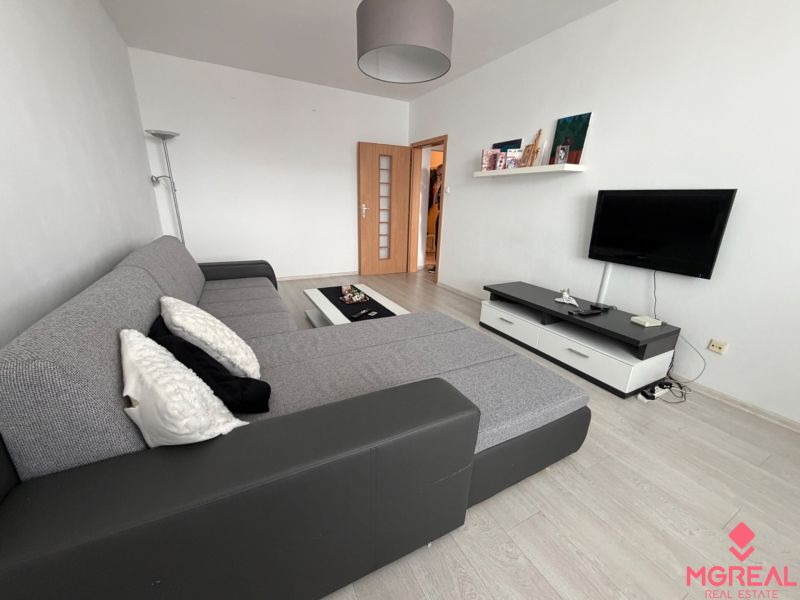 Wohnzimmer in einer Zweizimmerwohnung mit Holzboden und Ecksofa.