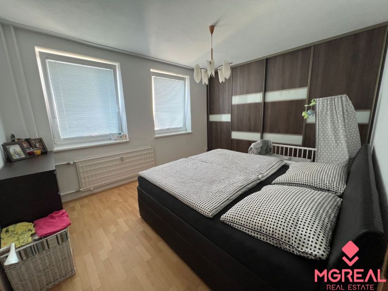 Schlafzimmer in einer 2-Zimmer-Wohnung mit Bett und Schrank, Boden mit Holzdekor.